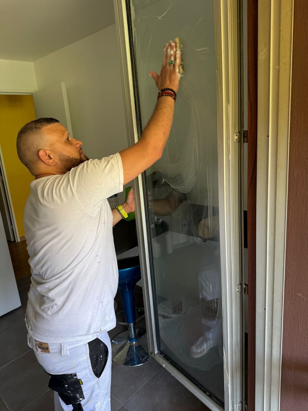 Artisan nettoyant une paroi de douche en fin de chantier